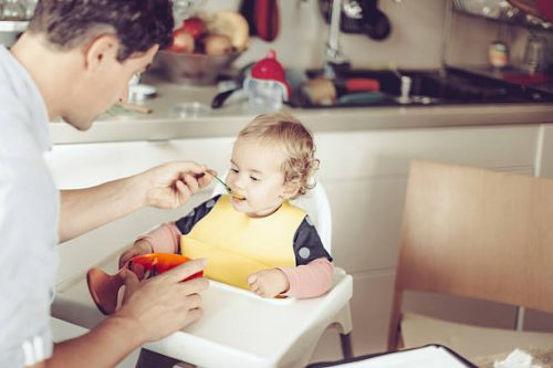 Papa en train de donner du fromage à son enfant dans la purée